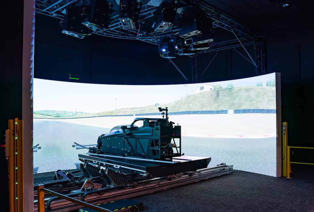 Un simulateur de course dans un centre technique, avec un kart sur un châssis de mouvement, écran de visualisation affichant un circuit.