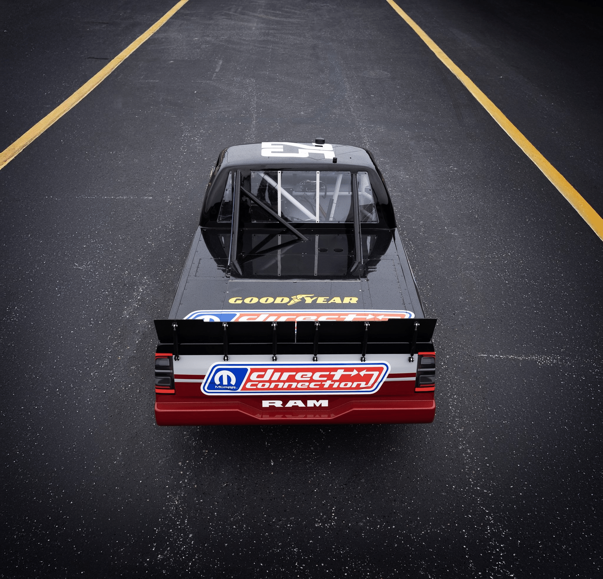 Vue aérienne d'un pickup Ram de la NASCAR Truck Series sur une piste, avec des logos Goodyear et Direct Connection.